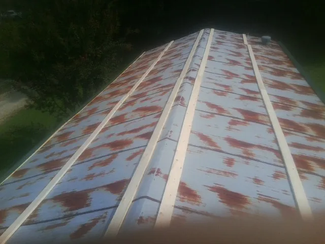 Rusted metal roof panels with new wood purlins before replacement — Storm Damage Roof Repair in Clarinda by Roofing Brothers