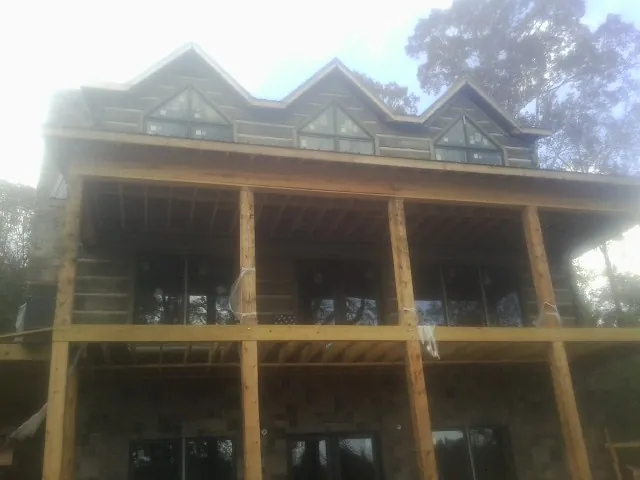 Dormers and porch framing on a large log home under construction — Roof Coating work by our crew in Clarinda