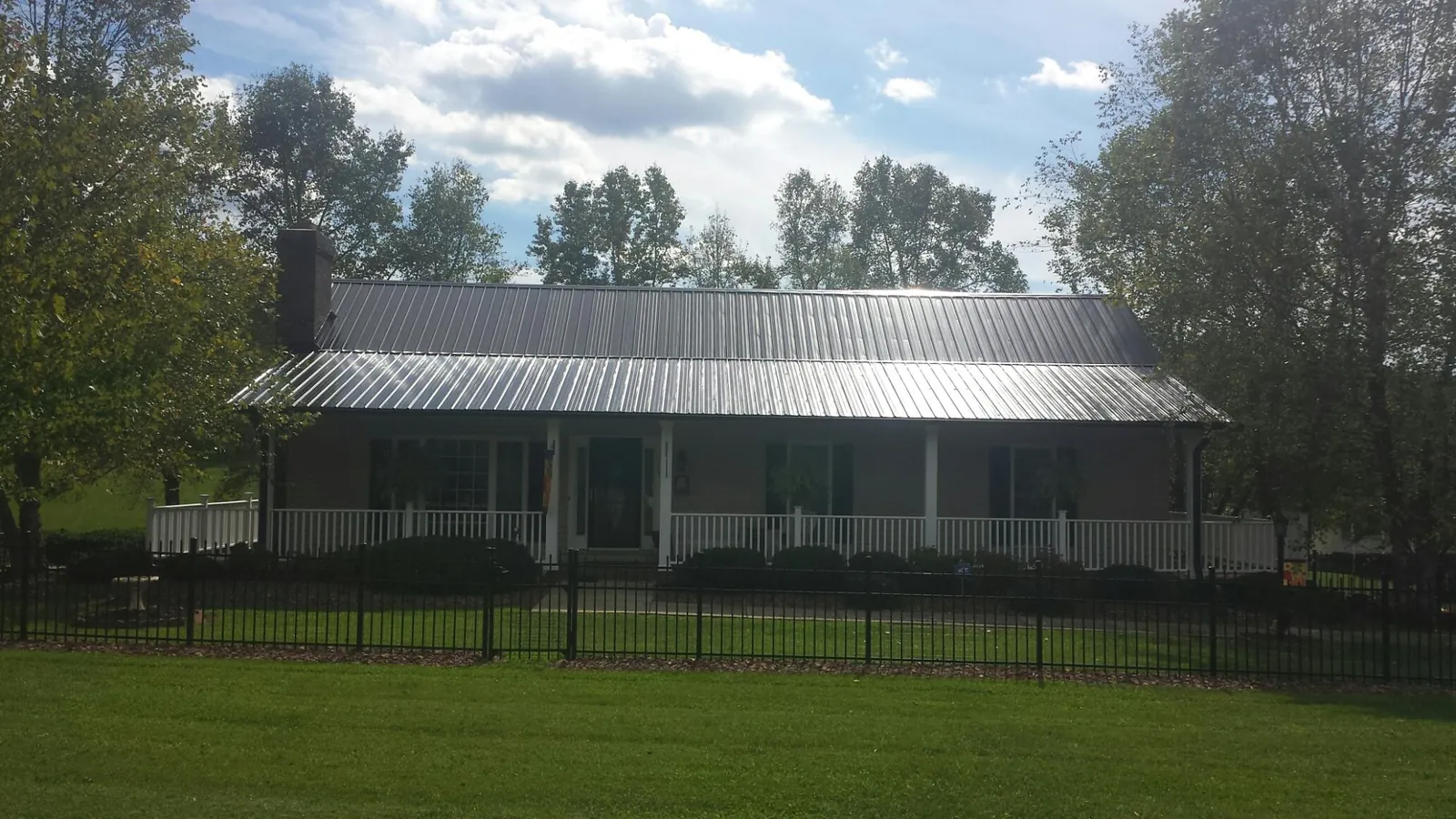 Gray metal roof on a brick ranch with a full width front porch — Gutter Guard Installation work by our crew in Clarinda