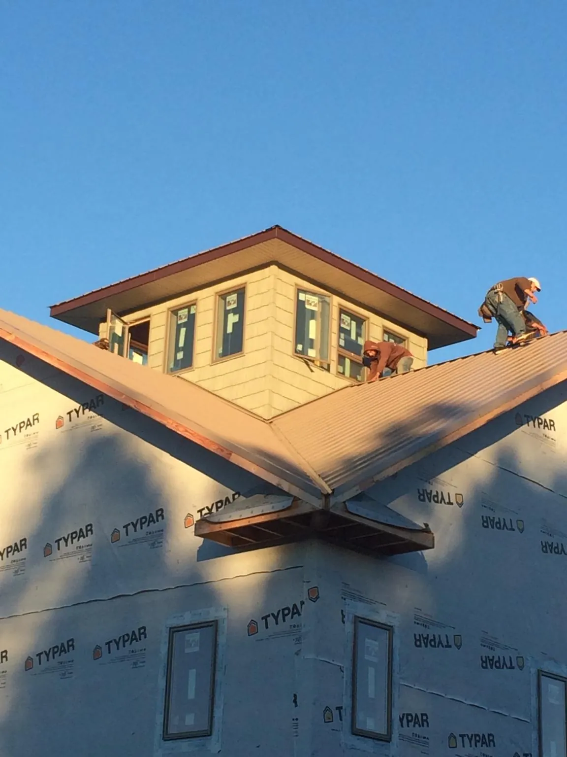 Roofers working around a rooftop cupola on a new metal roof at sunset — Roof Waterproofing in Clarinda by Roofing Brothers